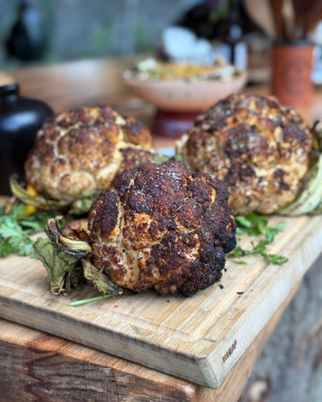 Roasted cauliflower on a wooden cutting board with a blurred background