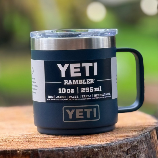YETI Rambler mug on a wooden surface with a blurred green background