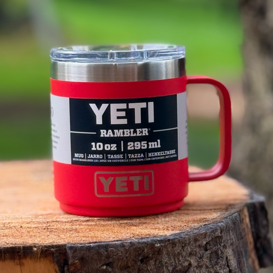 Red YETI Rambler mug on a wooden surface with a blurred green background